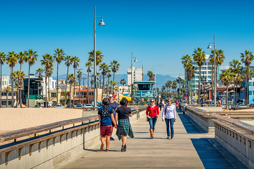 People walk on the Venice Beach Pier in Los Angeles, California, USA on a sunny day.