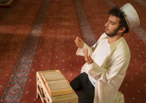 istock Muslim man reading quran and praying in mosque. 1388621946