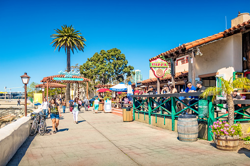 People enjoy the Seaport Village district in San Diego, California, USA on a sunny day.