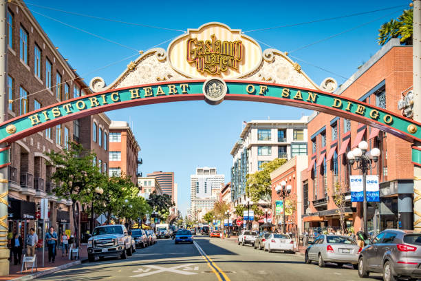 Pedestrians and cars move along 5th Avenue in the historic Gaslamp Quarter of downtown San Diego, California, USA on a sunny day.