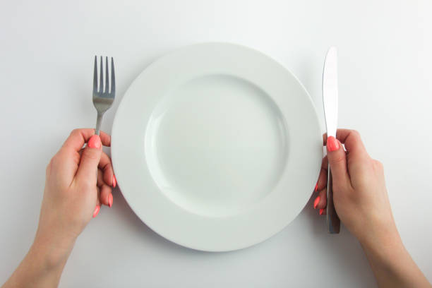istock Empty plate and female hands holding cutlery isolated on white background 1388622377