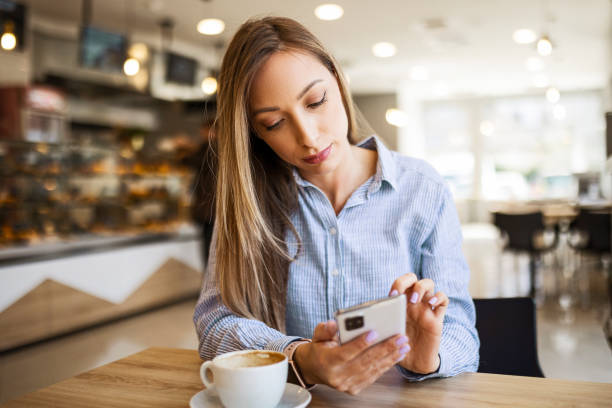 istock Young woman at restaurant drinking coffee and using phone text messaging 1388622949