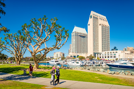 People walk on the waterfront promenade in downtown San Diego California, USA on a sunny day.