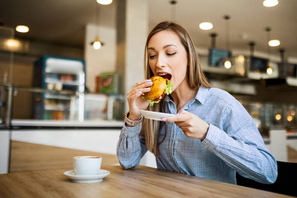 istock Young woman mouth open eating a small sandwich 1388622966