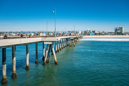 People walk and fish on the Venice Beach Pier in Los Angeles, California, USA on a sunny day.