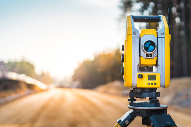 attrezzature per geometri (teodolite o stazione di posizionamento totale) sul cantiere della strada o dell'edificio con background di macchine edili - equipment accuracy laser nobody foto e immagini stock