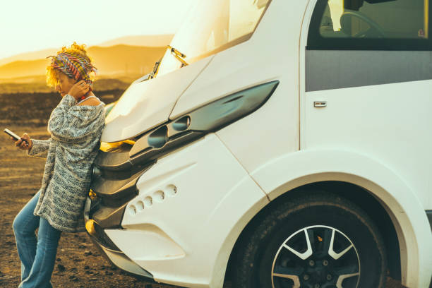 voyagez les gens style de vie van vie avec camping-car moderne. une jeune femme adulte jouit de la liberté contre un véhicule de camping-car utilisant un téléphone portable pour planifier le prochain voyage en voiture à destination. femme indépendant - nature travel locations photos et images de collection