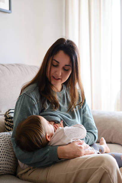 istock Mother breastfeeding her daughter while sitting on the sofa at home. 1388626036