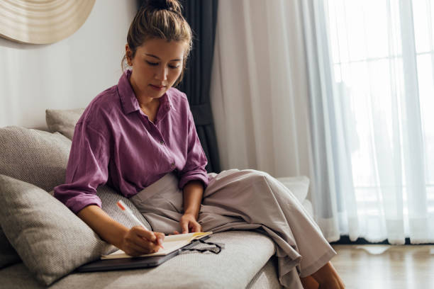 istock Asian Woman Planning Her Daily Activities In Her Notebook 1388627144