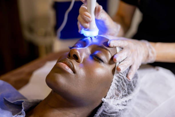 Woman at the spa getting an ultrasound treatment on her face African American woman at the spa getting an ultrasound treatment on her face with blue light therapy light therapy stock pictures, royalty-free photos & images