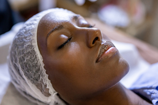 Beautiful African American woman at the spa getting a facial - beauty treatment concepts