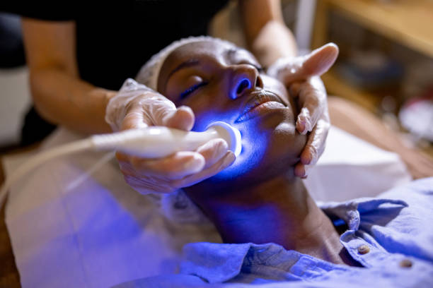 Woman at the spa getting a rejuvenation treatment on her face African American woman at the spa getting a rejuvenation treatment on her face using ultrasound and light therapy beautician equipment stock pictures, royalty-free photos & images