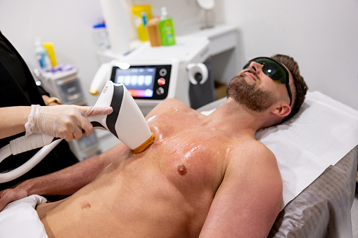 Handsome man getting a laser hair removal on his chest - beauty treatment concepts