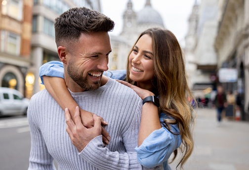 Loving couple having fun outdoors in London and smiling on the street while hugging