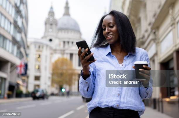 Business Woman Drinking Coffee On The Street While Checking Her Cell Phone Stock Photo - Download Image Now