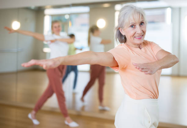 Mature female dancing with other women Portrait of elderly smiling european woman and people dancing in modern studio aerobics stock pictures, royalty-free photos & images