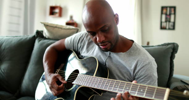 istock Black man practicing guitar at home. African mixed race learning to play musical instrument 1388630826