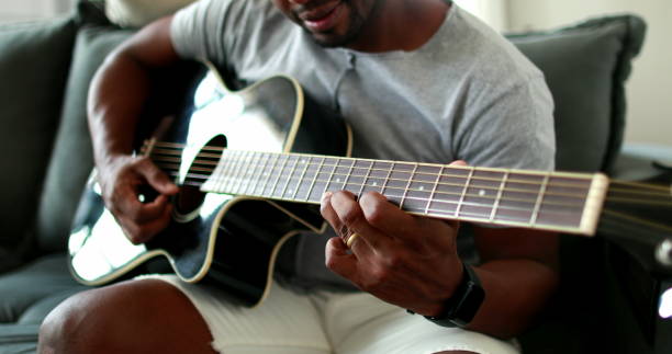 istock Black man practicing guitar at home. African mixed race learning to play musical instrument 1388631513