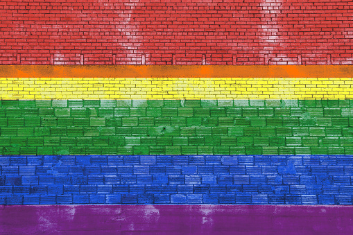 a symbolic rainbow painted brick stone wall yellow red green blue purple gay rights pride flag colors social symbol mural