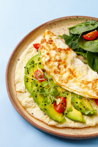 istock Dish with egg omelette with avocado and green spinach. Close up, blue background 1388634416