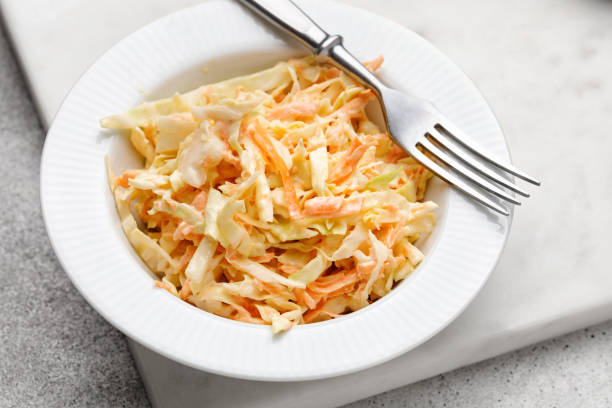 salade de chou coleslaw avec chou, carottes, herbes et graines de sésame sur une assiette blanche. alimentation saine, nourriture végétalienne - cole photos et images de collection