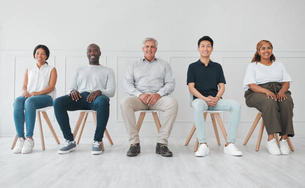 portrait d’un groupe diversifié de personnes assises en ligne sur un fond blanc - people in a row in a row human face smiling photos et images de collection