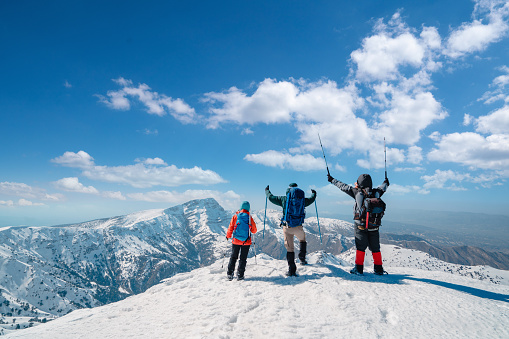 Alpinist climbers are looking at the camera while watching the landscape of beautiful summit of the high altitude mountain.