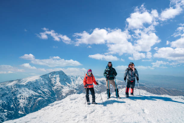 istock Successful mountain climber team is looking at camera while holding hiking poles on peak of the high altitude snowy mountain summit in winter 1388640504