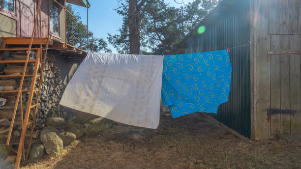 istock Bedding sheets drying on the clothesline outside. Lens flare. Bed linen drying on a clothes line in the garden. 1388641495