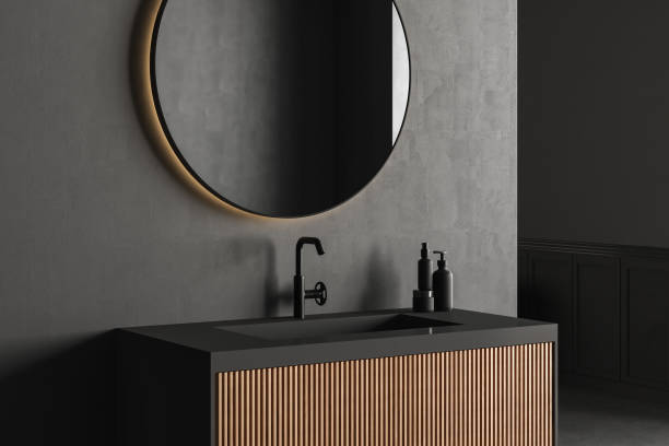 Close up of sink with oval mirror standing in on black wall stock photo