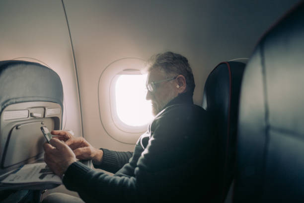 istock Senior man using a phone on board the aircraft 1388641897