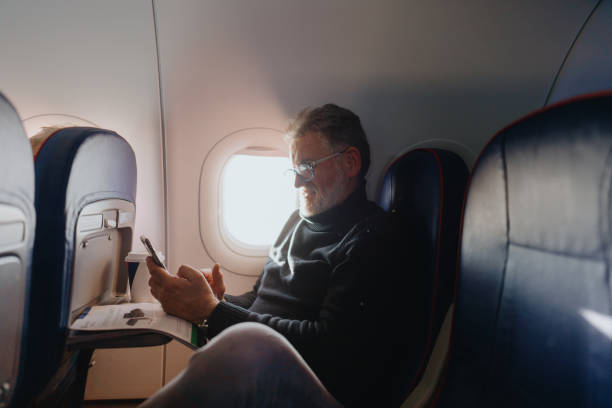 istock Senior man using a phone on board the aircraft 1388641943