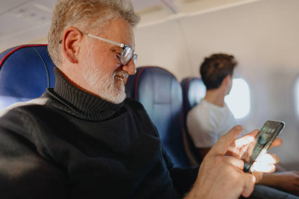 istock Senior man using a phone on board the aircraft 1388641947