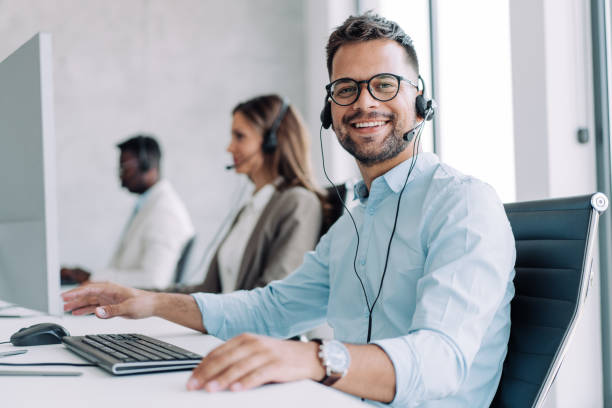 Call center workers. Shot of call center operators working in the office. Call center agent working with his colleagues in modern office. Smiling handsome businessman working in call center. customer service representative stock pictures, royalty-free photos & images