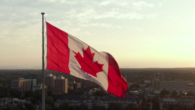 Aerial Orbiting Shot Showing Canadian Flag Waving in the Wind Against the Sun on Canada Day in Calgary, Alberta, Canada