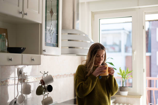 istock Woman standing in the kitchen and drinking cup of tea 1388644082