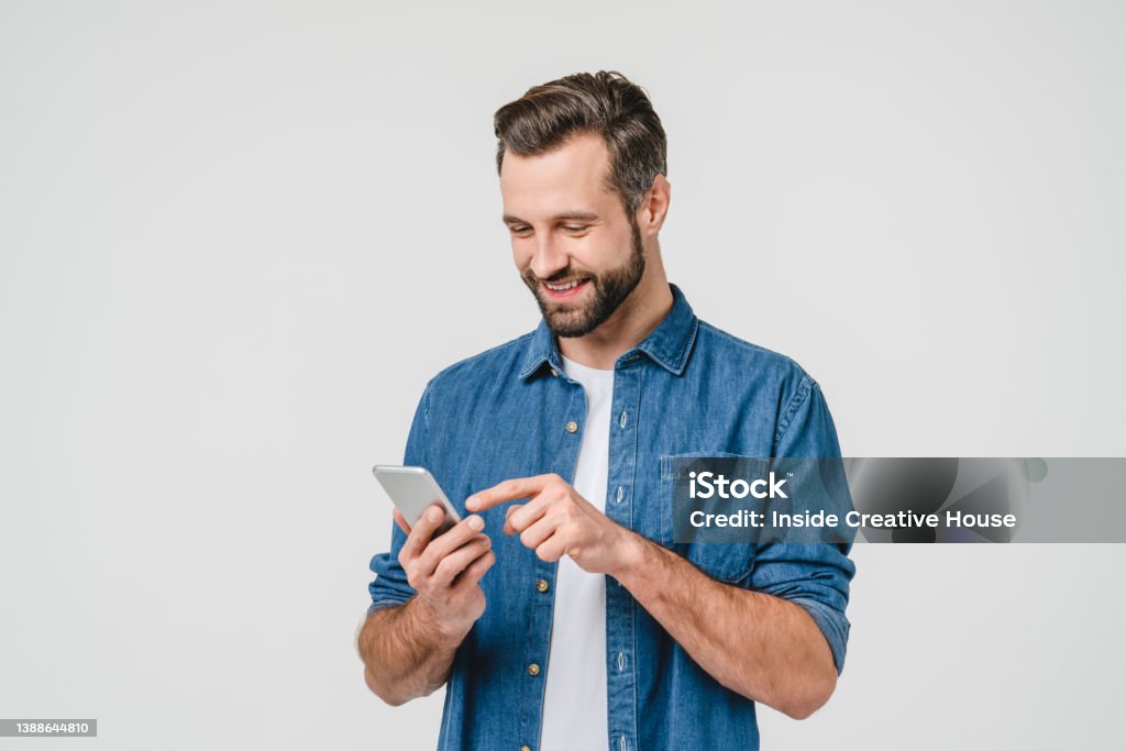 Happy caucasian young man using smart phone cellphone for calls, social media, mobile application online isolated in white background Mobile Phone Stock Photo