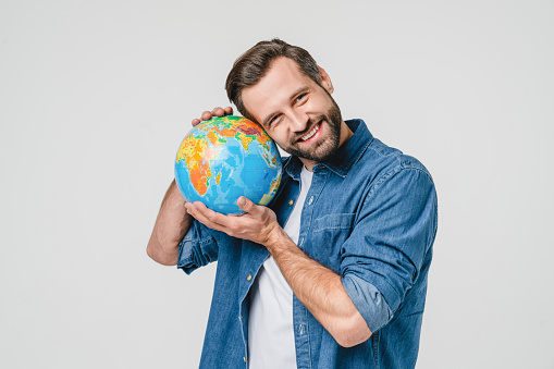 Geography concept. Caucasian young male eco-activist hugging embracing Earth globe with care, protecting planet from contamination, garbage, traveling abroad isolated in white background