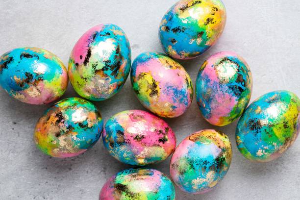 istock Happy Easter holiday greeting card with gold, blue, yellow, pink painted speckled easter eggs on grey background. Top view. 1388645024