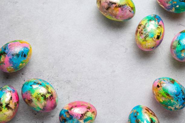 istock Happy Easter holiday greeting card. Frame with gold, blue, yellow, pink painted speckled easter eggs on grey background. Top view, copy space for text. 1388645026