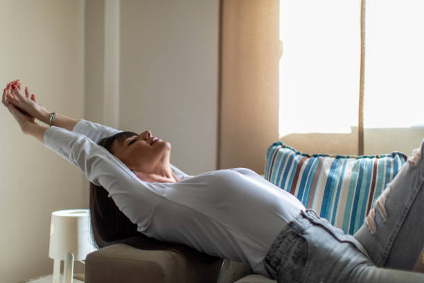 Beautiful woman relaxing at home on sofa. She looks happy while  lying down and starching.