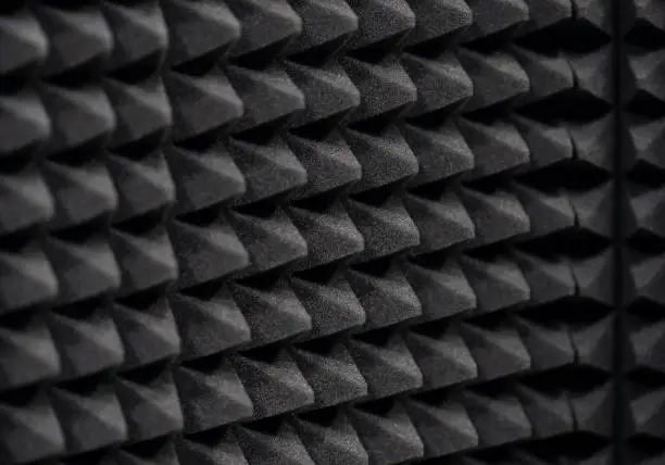 Photo of Sound insulation, audio isolation acoustic foam panel, wall tiles, recording studio room soundproofing equipment accessories, object detail, closeup, dark grey background texture, nobody, shallow dof