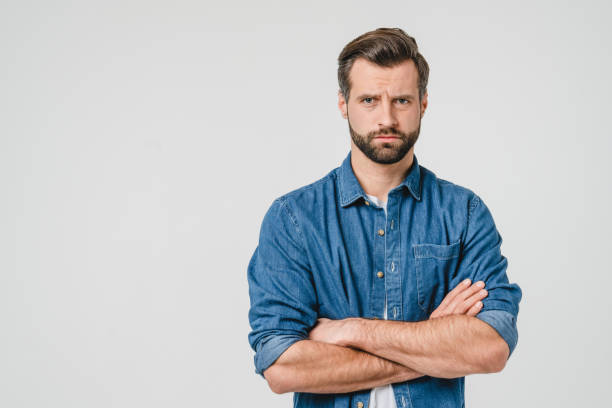 offeso triste arrabbiato giovane caucasico con le braccia incrociate soffiandosi le labbra guardando la telecamera isolata su sfondo bianco. concetto di rabbia conflittuale - displeased foto e immagini stock