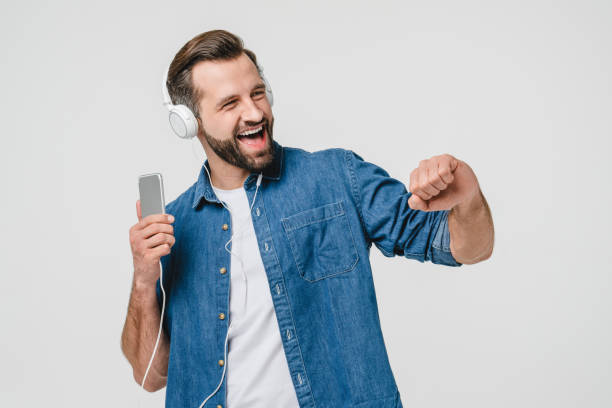 istock Vivid caucasian young man student freelancer using mobile application for listening to the music, podcast, sounds, dancing and singing on white background 1388646244