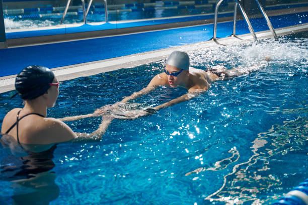 istock Coach helping male to swim in pool 1388647234