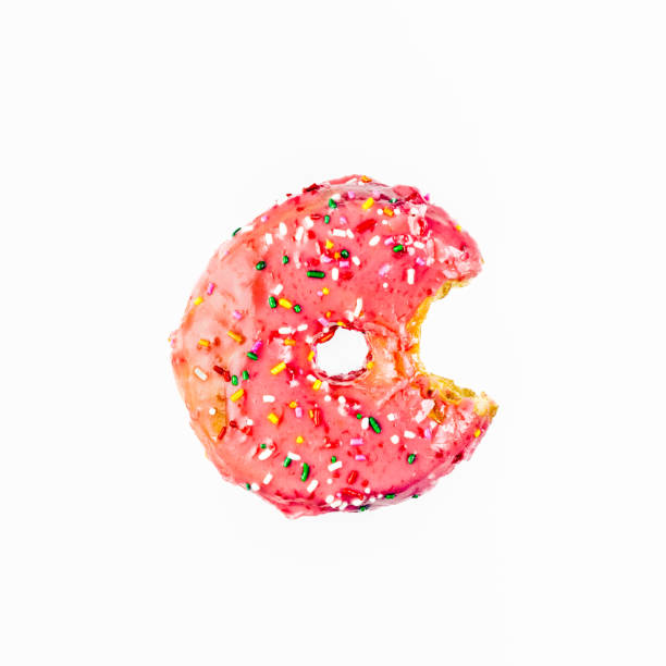 Top down view of a Pink Donut with a bite missing and candy sprinkles on white with copy space.