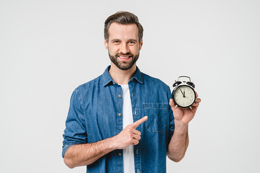 Smiling caucasian young man freelancer student holding alarm clock for deadline, being late, high time for sale discount offer isolated in white background