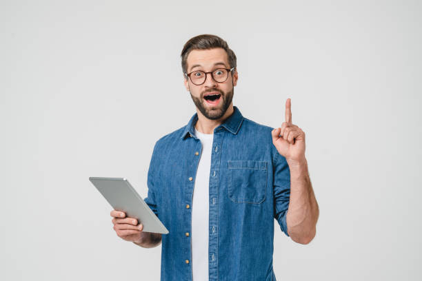 istock Young happy impressed caucasian man student in glasses using digital tablet for e-learning, watching video, webinars having idea, pointing upwards isolated in white background 1388649938