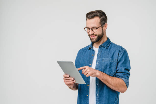 alegre joven caucásico estudiante independiente que usa una tableta digital para redes sociales, banca electrónica, aplicación móvil, aprendizaje electrónico aislado en fondo blanco - tableta digital fotografías e imágenes de stock