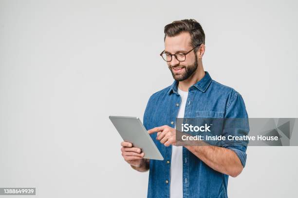 Cheerful Caucasian Young Man Student Freelancer Using Digital Tablet For Social Media Ebanking Mobile Application Elearning Isolated In White Background Stock Photo - Download Image Now